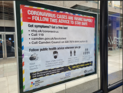 a large sign about coronavirus at a bus stop